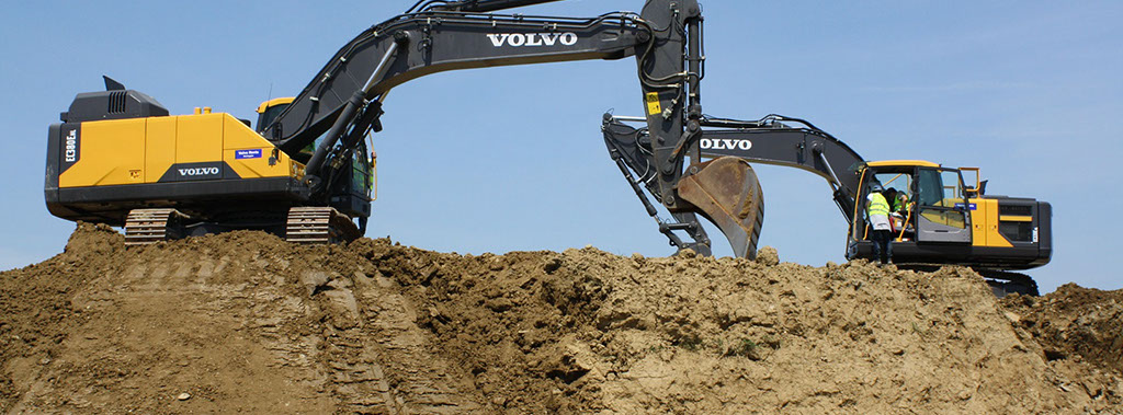 zwei Bagger heben Erde aus einem Loch und planieren den Untergrund